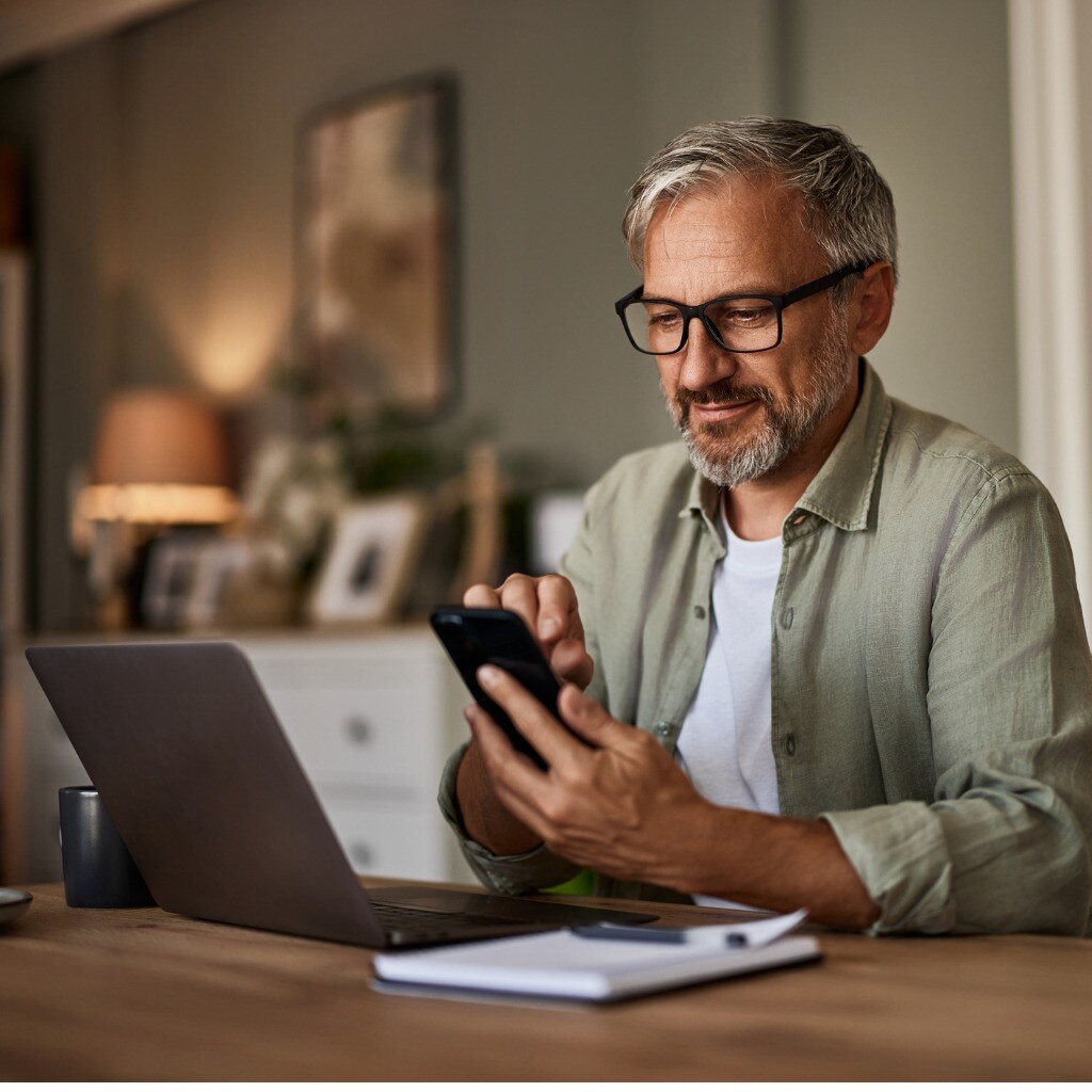 a-smiling-male-freelancer-with-eyeglasses-using-a-phone-while-working-over-a-laptop.jpg_s=1024x1024&w=is&k=20&c=worCS5Mk4P_p4OpsofqJXWZWDwjXE58Gbkm_oXDzTok= (1)