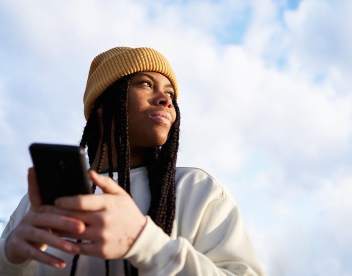 Young person accessing dermatology care through their smart phone.